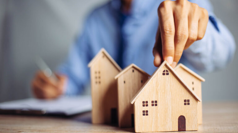 Businessman,Choosing,Mini,Wood,House,Model,From,Model,On,Wood